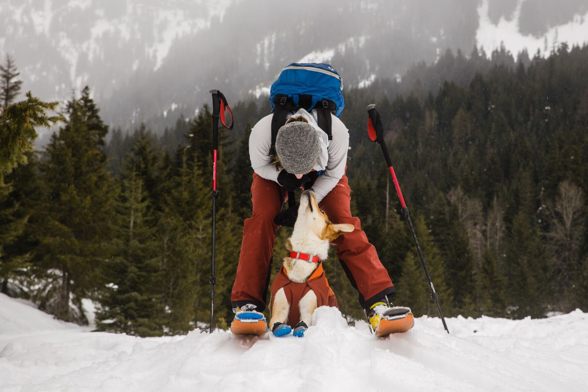 Woman petting her dog in the snow.
