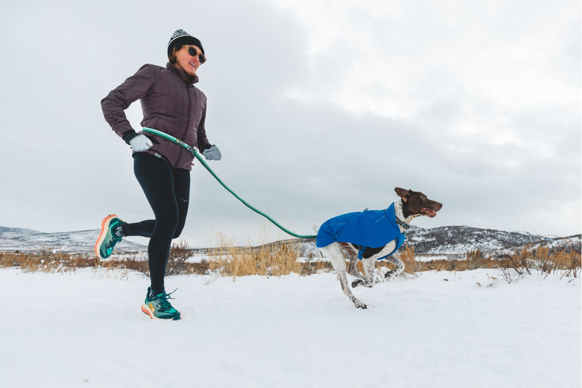 Woman running with her dog in the snow.